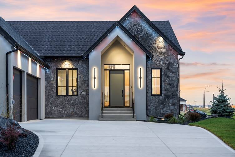 Stone and stucco home exterior with architectural wall sconces at sunset